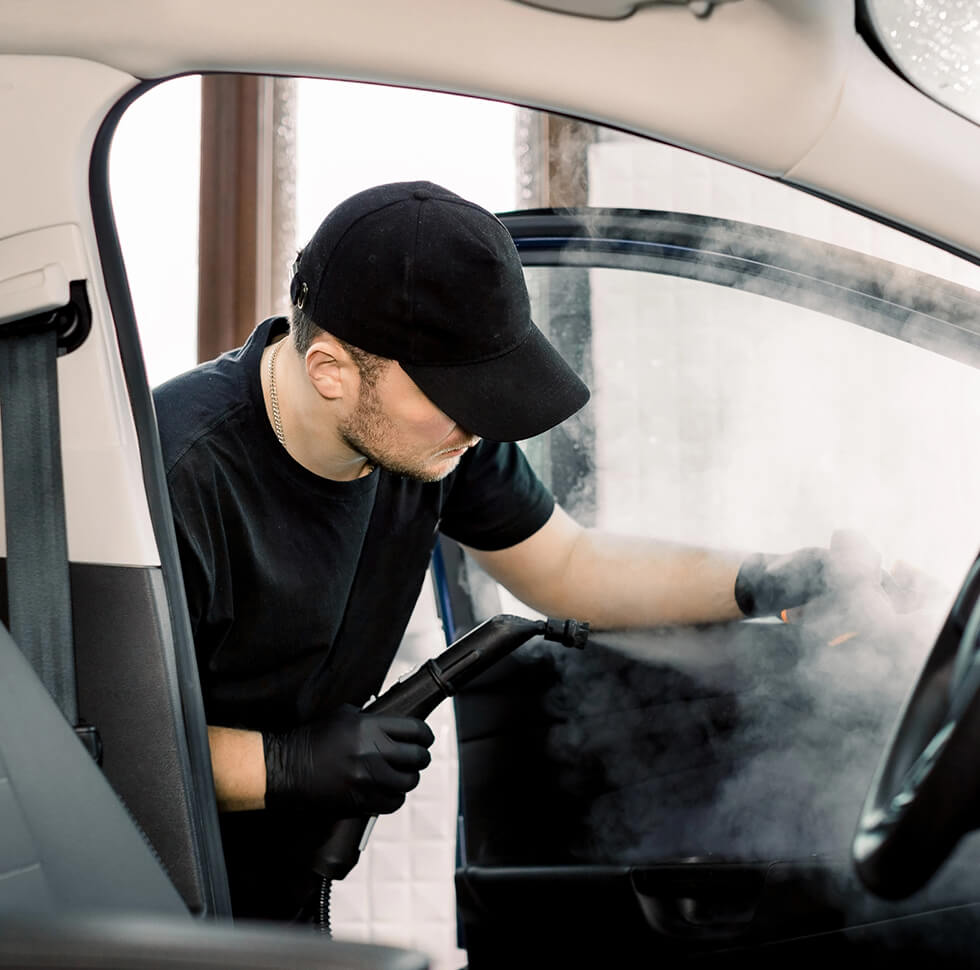 Un homme nettoie l'intérieur d'un véhicule un nettoyant vapeur